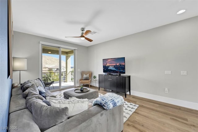 living room featuring light wood-style flooring, a ceiling fan, and baseboards