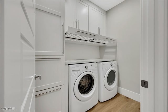 washroom with washer and dryer, baseboards, cabinet space, and light wood finished floors