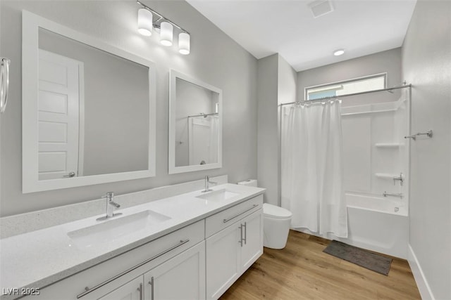 bathroom featuring wood finished floors, toilet, shower / tub combo with curtain, and a sink