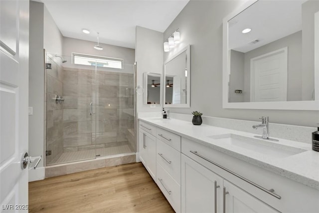 full bath with visible vents, a stall shower, wood finished floors, and a sink