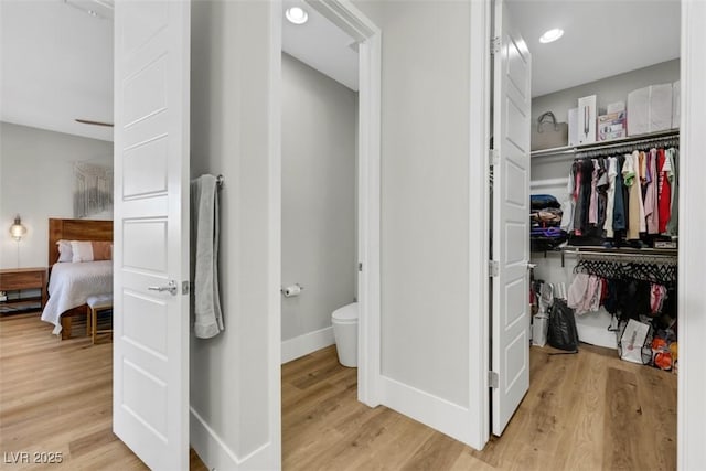 bathroom with baseboards, ensuite bath, wood finished floors, and toilet