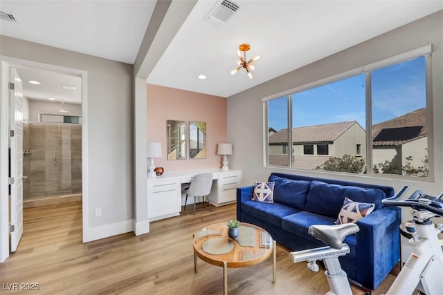 living area with light wood-type flooring, baseboards, visible vents, and built in study area