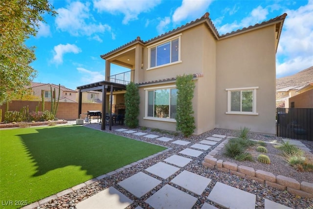 back of property featuring stucco siding, a patio, a yard, a balcony, and fence private yard