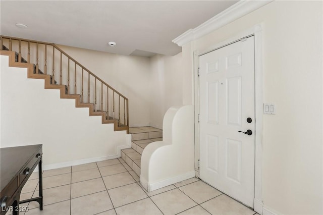 foyer entrance featuring light tile patterned floors, baseboards, and stairs