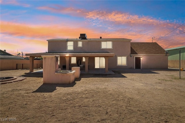 rear view of house with a patio area, stucco siding, and fence