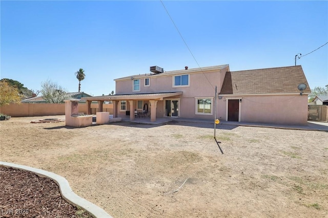 rear view of property with stucco siding, an outdoor fire pit, a patio, and fence