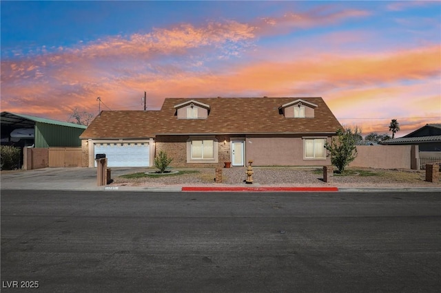 view of front of house featuring stucco siding, driveway, an attached garage, and fence