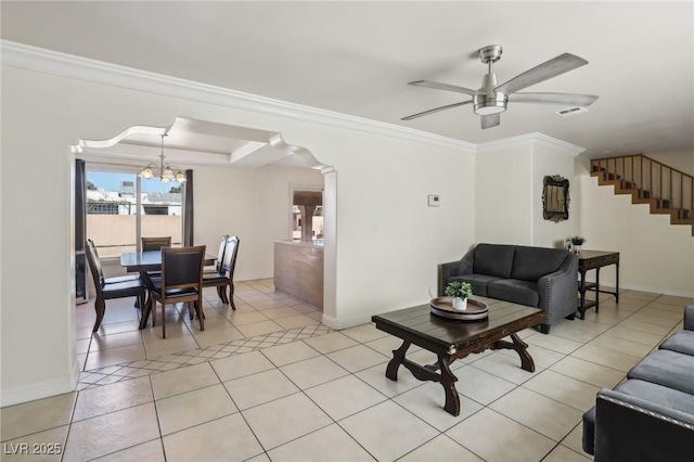 living area with visible vents, ornamental molding, ceiling fan with notable chandelier, stairway, and light tile patterned floors