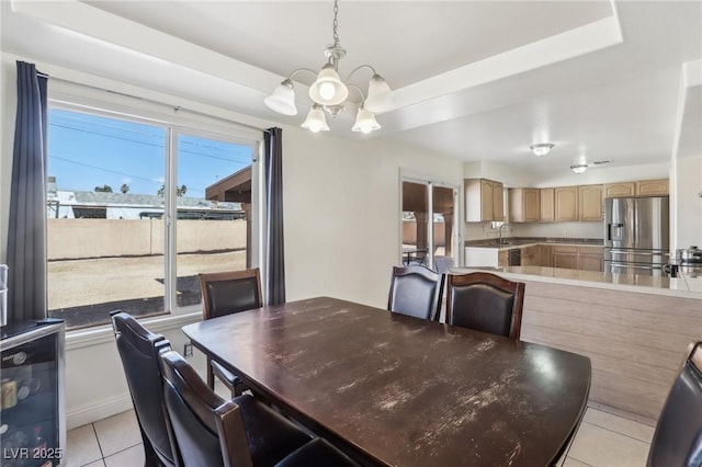 dining area featuring an inviting chandelier, light tile patterned floors, and a tray ceiling