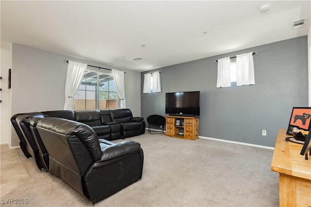 living room featuring light colored carpet, a healthy amount of sunlight, visible vents, and baseboards