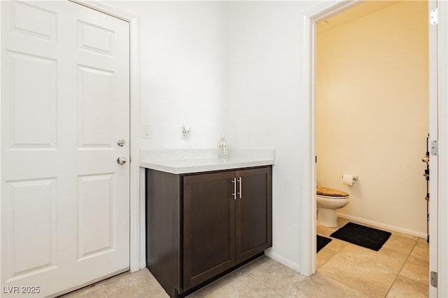 bathroom featuring toilet, vanity, and baseboards