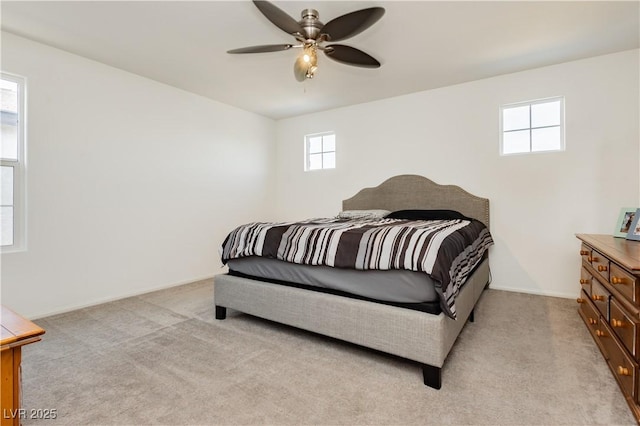 bedroom featuring light colored carpet, baseboards, and ceiling fan