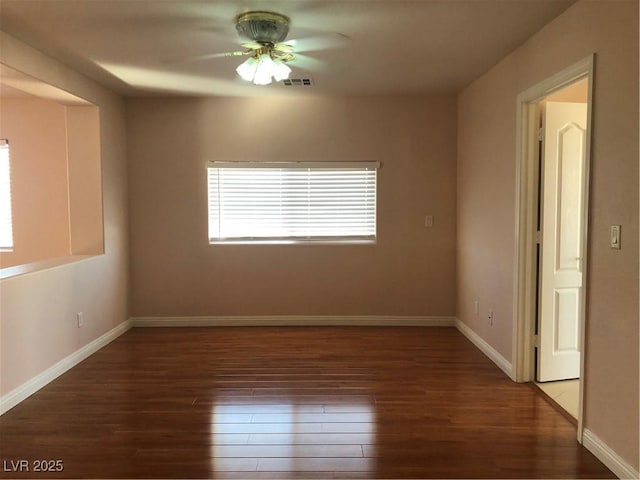 empty room with a ceiling fan, wood finished floors, visible vents, and baseboards