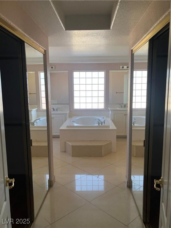 bathroom with tile patterned floors, plenty of natural light, a garden tub, and a textured ceiling