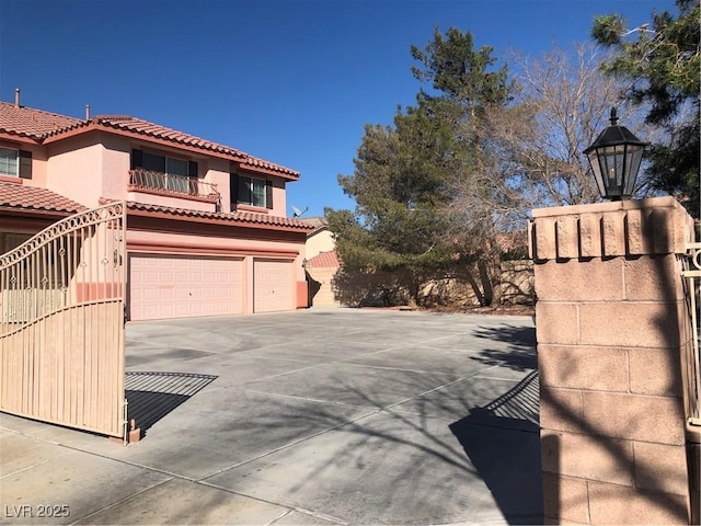 exterior space with stucco siding, driveway, a tile roof, and a garage