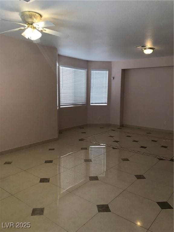 spare room with baseboards, light tile patterned flooring, and a ceiling fan