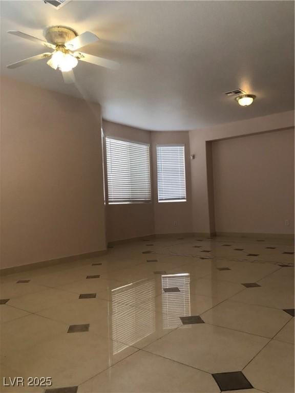 tiled spare room with visible vents, baseboards, and ceiling fan