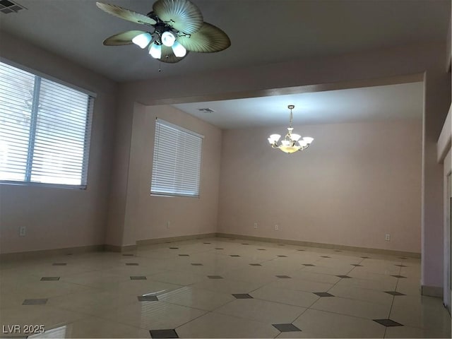 unfurnished room featuring tile patterned floors, ceiling fan with notable chandelier, visible vents, and baseboards