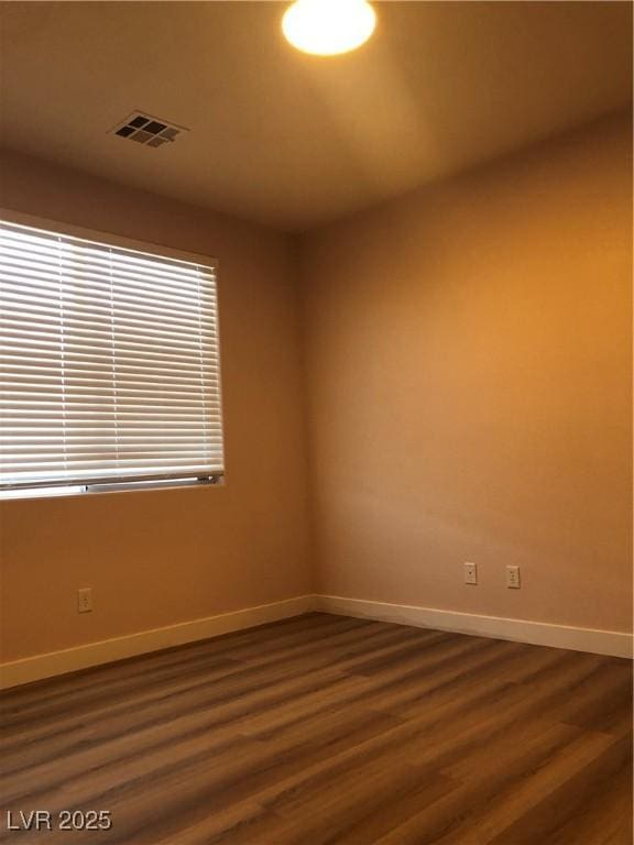 spare room featuring dark wood-style floors, visible vents, and baseboards