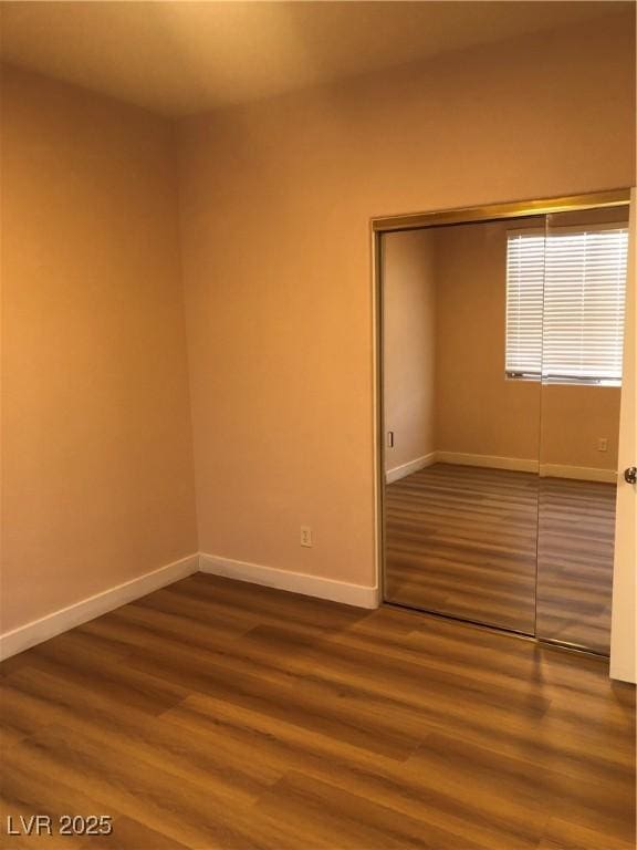 interior space with a closet, dark wood-type flooring, and baseboards