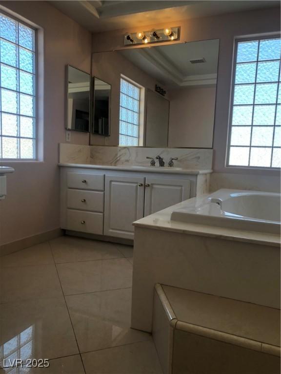 bathroom with visible vents, tile patterned flooring, baseboards, a bath, and vanity