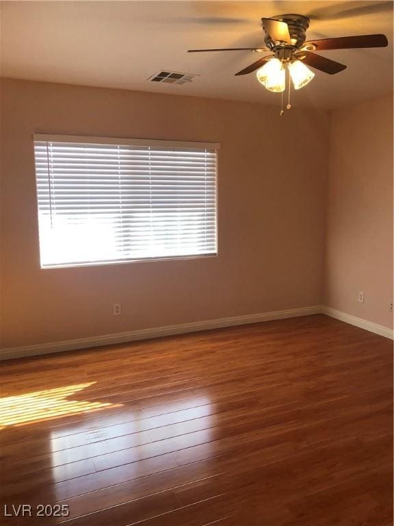 spare room featuring visible vents, ceiling fan, baseboards, and hardwood / wood-style floors