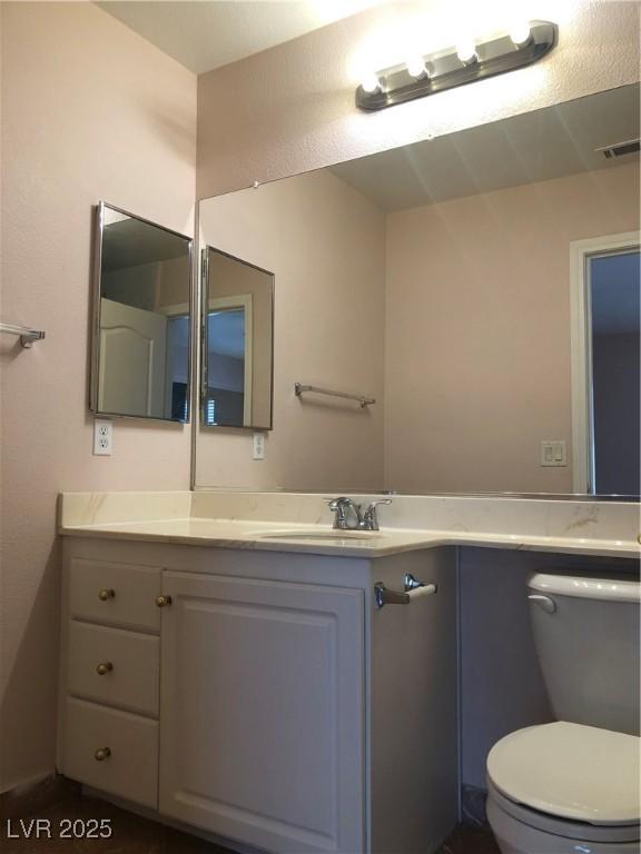 bathroom featuring visible vents, toilet, and vanity