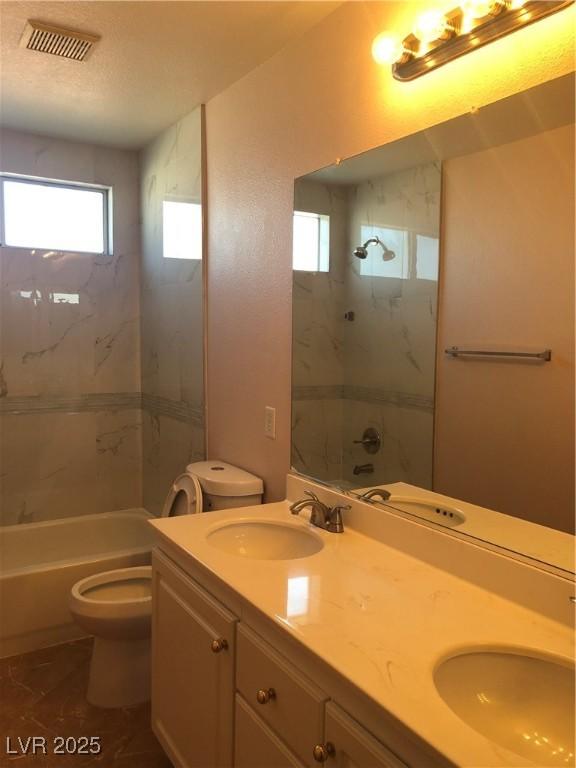 bathroom with double vanity, toilet, and a sink