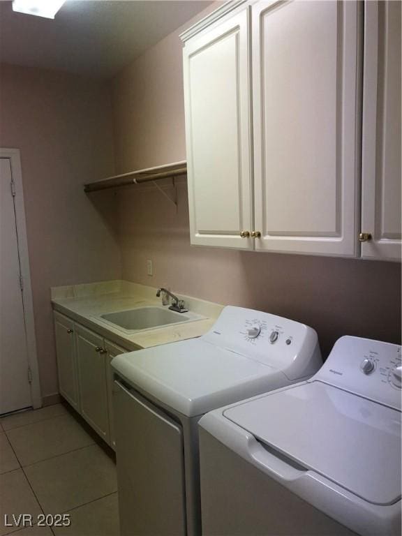 washroom with light tile patterned floors, cabinet space, a sink, and washing machine and clothes dryer