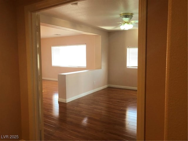 spare room featuring dark wood-style floors and baseboards