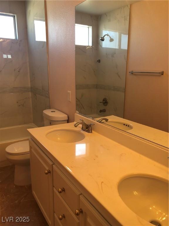 full bathroom with double vanity, toilet, and a sink