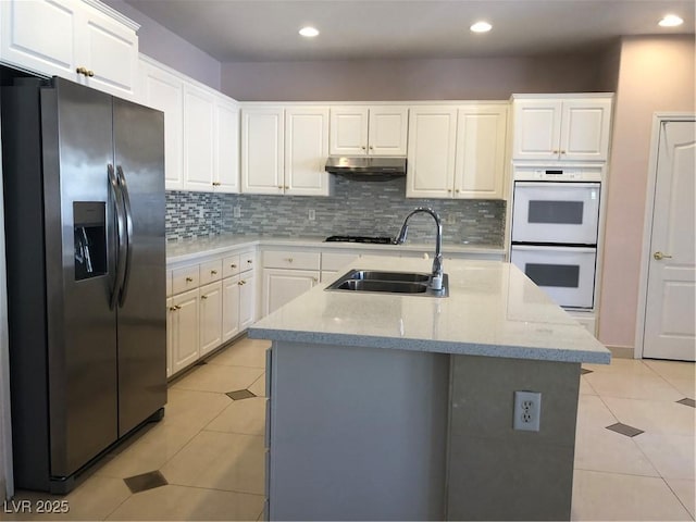 kitchen featuring backsplash, white double oven, stainless steel refrigerator with ice dispenser, light tile patterned flooring, and a sink