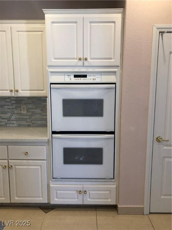 kitchen featuring white cabinetry, double oven, light tile patterned floors, and light countertops