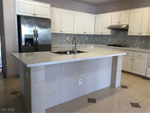 kitchen featuring light tile patterned floors, stainless steel fridge with ice dispenser, a sink, under cabinet range hood, and backsplash