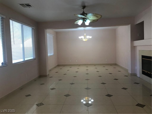 unfurnished living room with visible vents, baseboards, a fireplace, and ceiling fan with notable chandelier