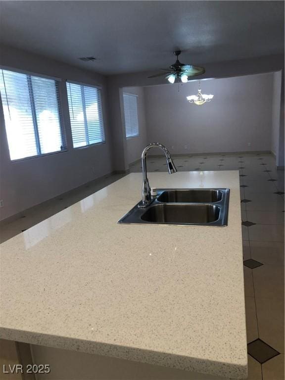 kitchen featuring open floor plan, light stone countertops, visible vents, and a sink