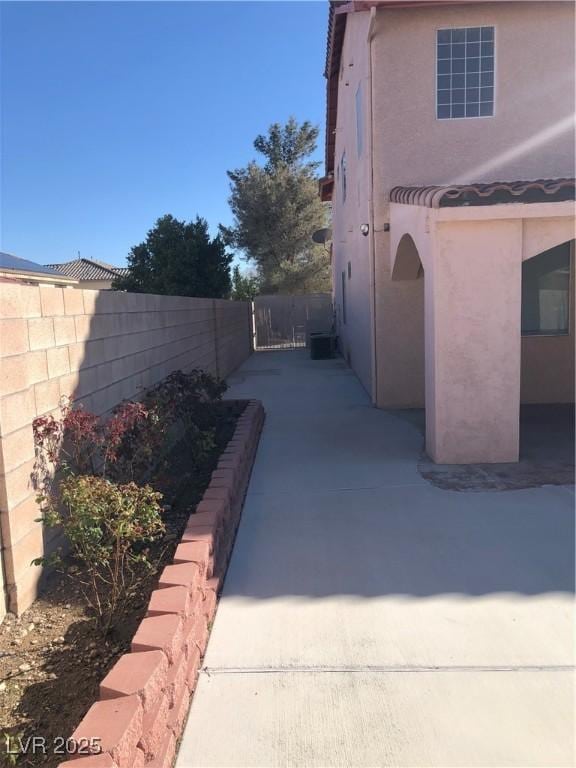 view of side of home featuring a patio area, fence, and stucco siding