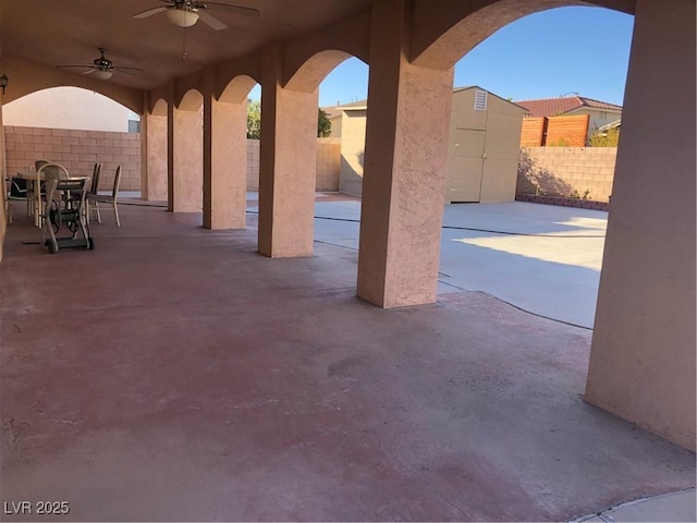 view of patio / terrace featuring a storage unit, a fenced backyard, an outbuilding, and ceiling fan