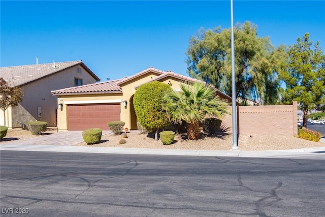 view of front of home with stucco siding, a garage, driveway, and a tile roof