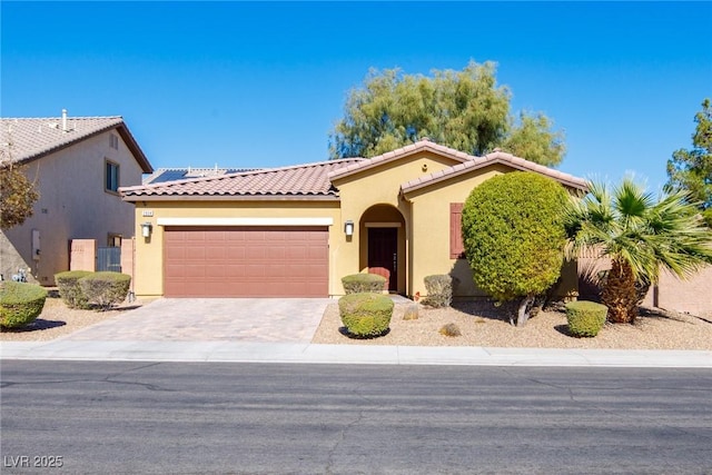 mediterranean / spanish-style house with stucco siding, an attached garage, driveway, and a tile roof