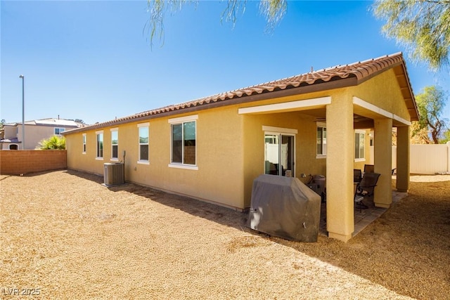 view of side of home featuring stucco siding, a patio area, central AC, and fence