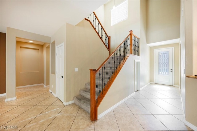 stairway with tile patterned floors, baseboards, and a towering ceiling