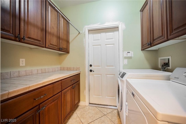 washroom featuring washer and clothes dryer, cabinet space, and light tile patterned flooring