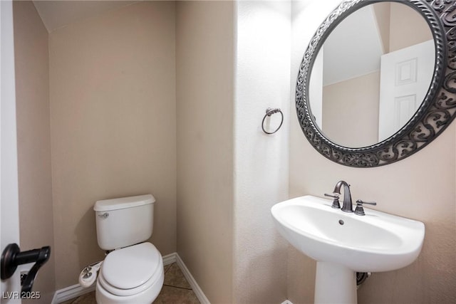 bathroom with a sink, baseboards, toilet, and tile patterned flooring