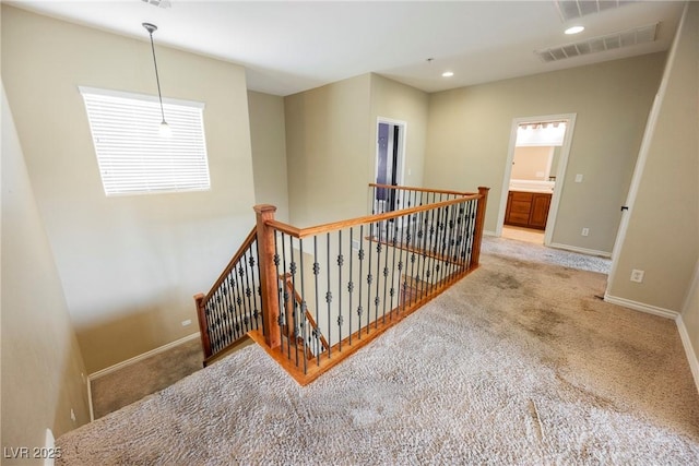 corridor with visible vents, baseboards, carpet floors, an upstairs landing, and recessed lighting