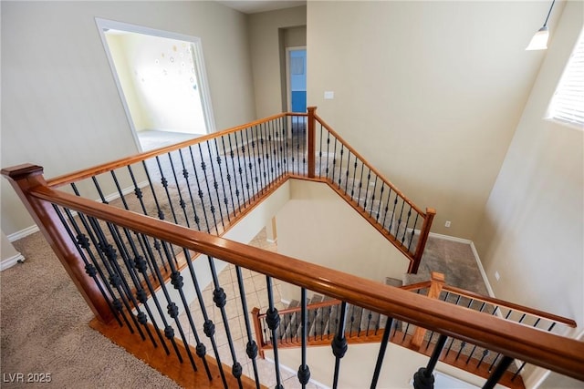 stairway with carpet flooring, baseboards, and a towering ceiling