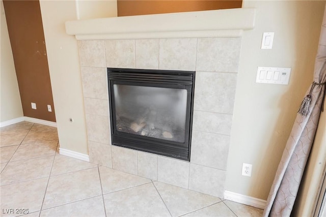 interior details featuring a tiled fireplace and baseboards