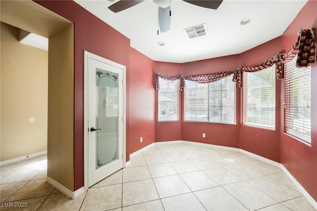 spare room with light tile patterned floors, visible vents, a ceiling fan, and baseboards