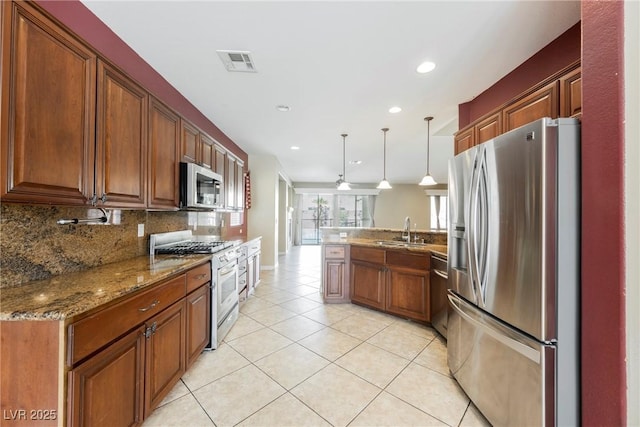 kitchen with tasteful backsplash, visible vents, a peninsula, stainless steel appliances, and a sink