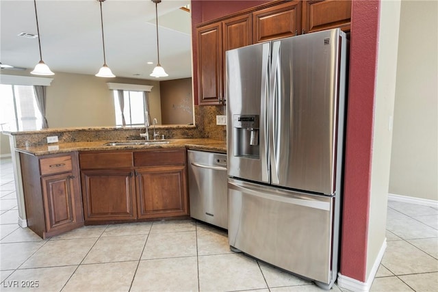 kitchen with a sink, tasteful backsplash, stainless steel appliances, a peninsula, and light tile patterned floors